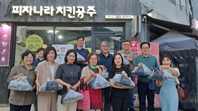 교수들이 후원의 집인 「피자나라 치킨공주」 앞에서 포장 음식 봉투를 들고 기념 촬영한 모습