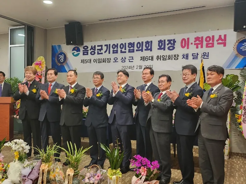 「음성군기업인협의회 회장 이·취임식」 현수막 앞에서 내빈들이 박수를 치는 모습