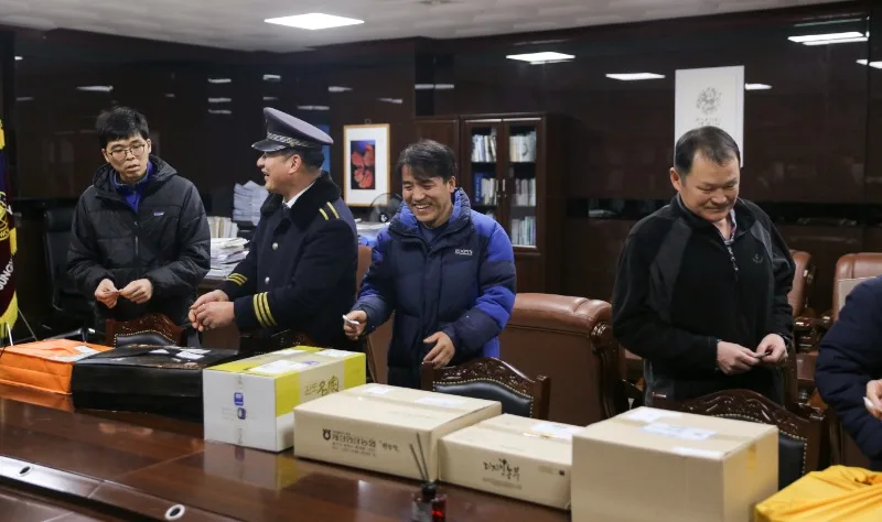 직원들이 탁자 위 선물 상자 앞에서 뽑은 제비를 확인하는 모습
