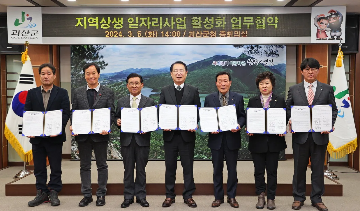 「지역상생 일자리사업 활성화 업무협약」(2024년 3월 5일, 괴산군청 중회의실) 현수막 앞에서 황윤원 총장과 협약 기관·단체 대표들이 협약서를 들고 있는 모습